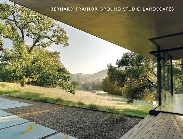 A modern glass building overlooks a grassy landscape with large trees and rolling hills under a clear sky—an inspiring scene perfect for architect gifts or student gifts, labeled Bernard Trainor Ground Studio Landscapes.